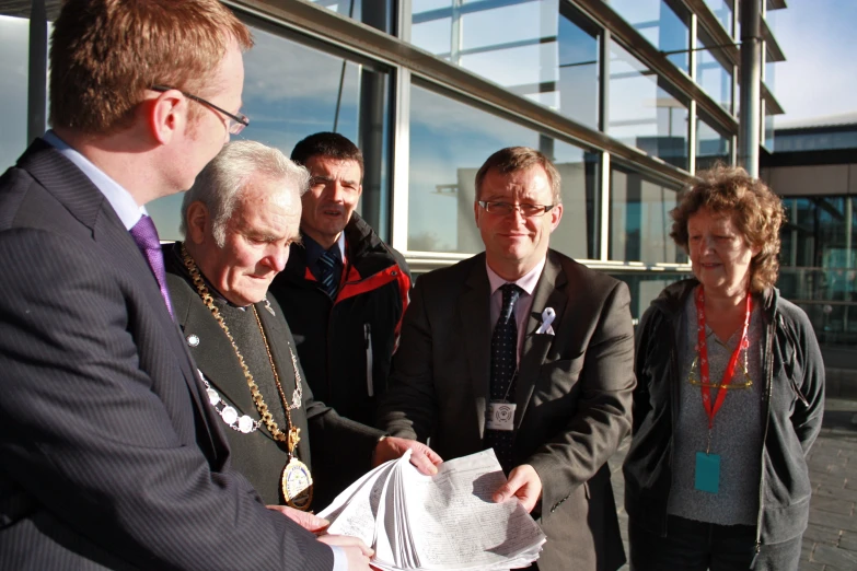 two men shaking hands in front of some other men and a building