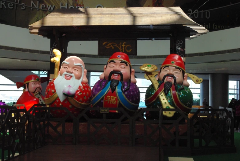 a line of statue on display behind a metal fence