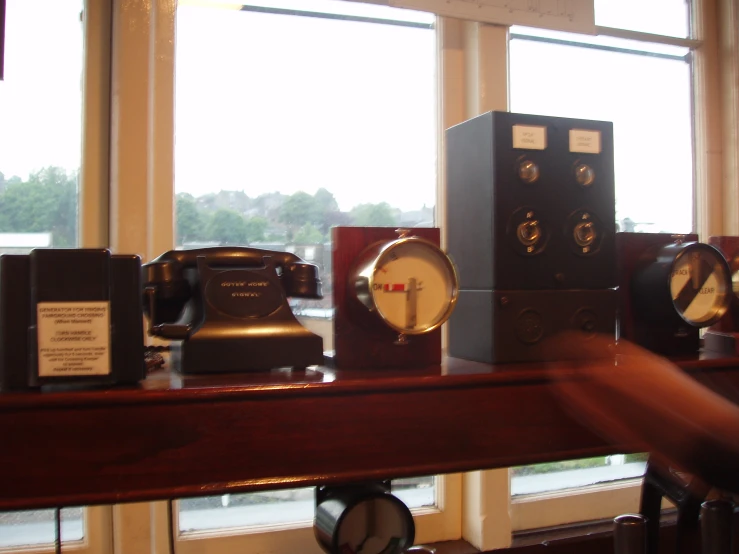 assorted clocks on a desk in a room with large windows