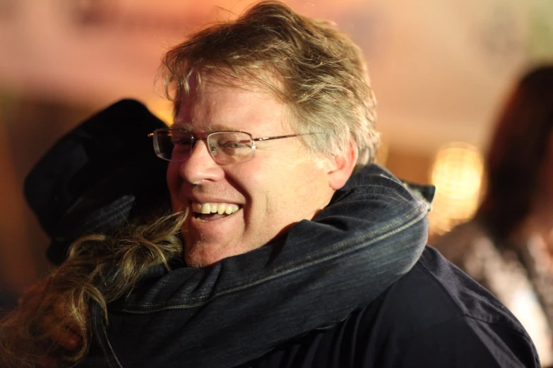 man wearing glasses laughing and wearing a neck scarf