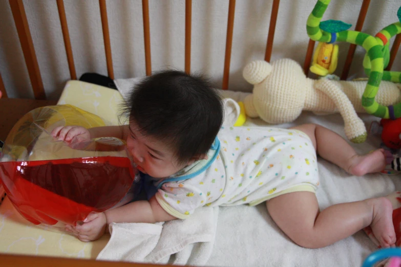 the baby is laying in his crib playing with his toys