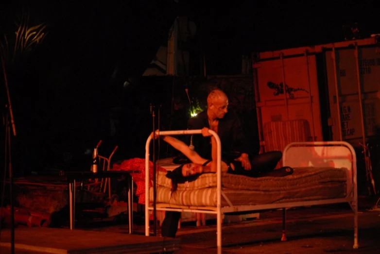 two people sitting on the bed in the dark