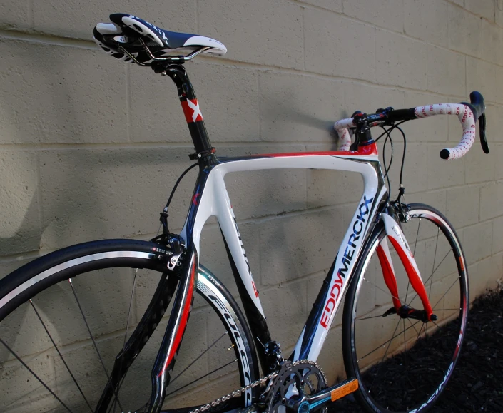 a white and red bike leaning against a wall