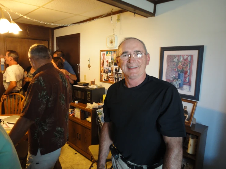 a man stands smiling in front of a group of friends