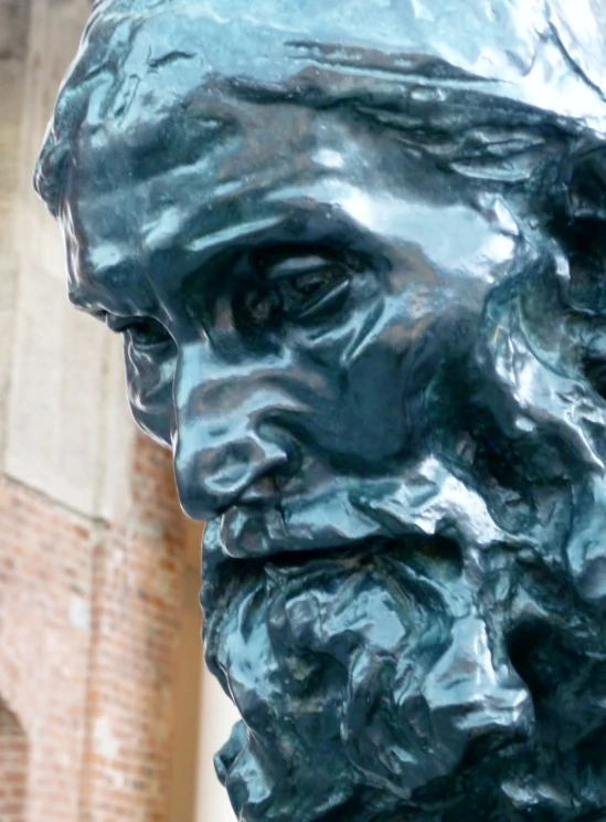 a green statue with a mustache in front of a brick wall