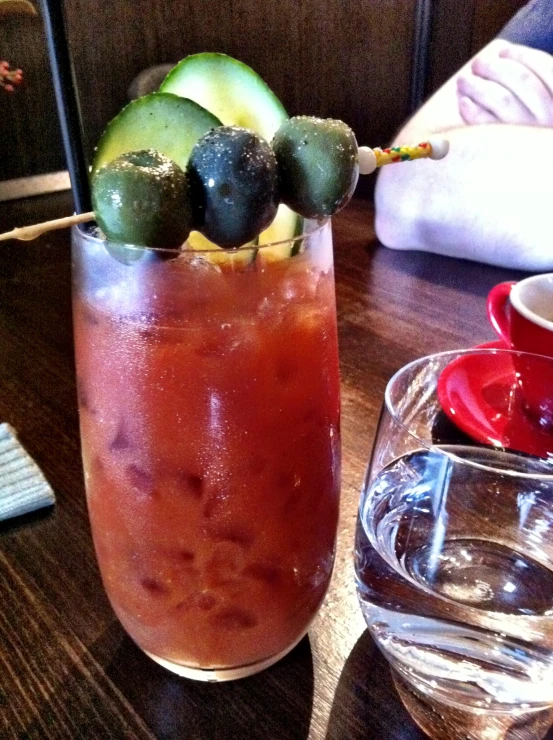 a glass full of drink sitting on top of a wooden table