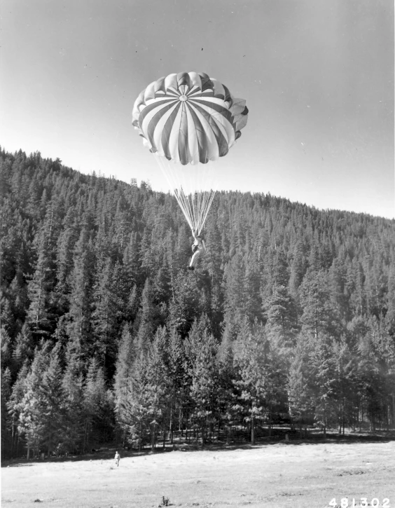 a large air ballon in the sky above a tree lined mountain