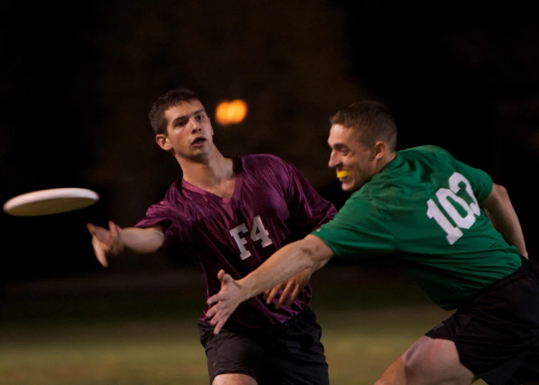 two men playing frisbee at the park