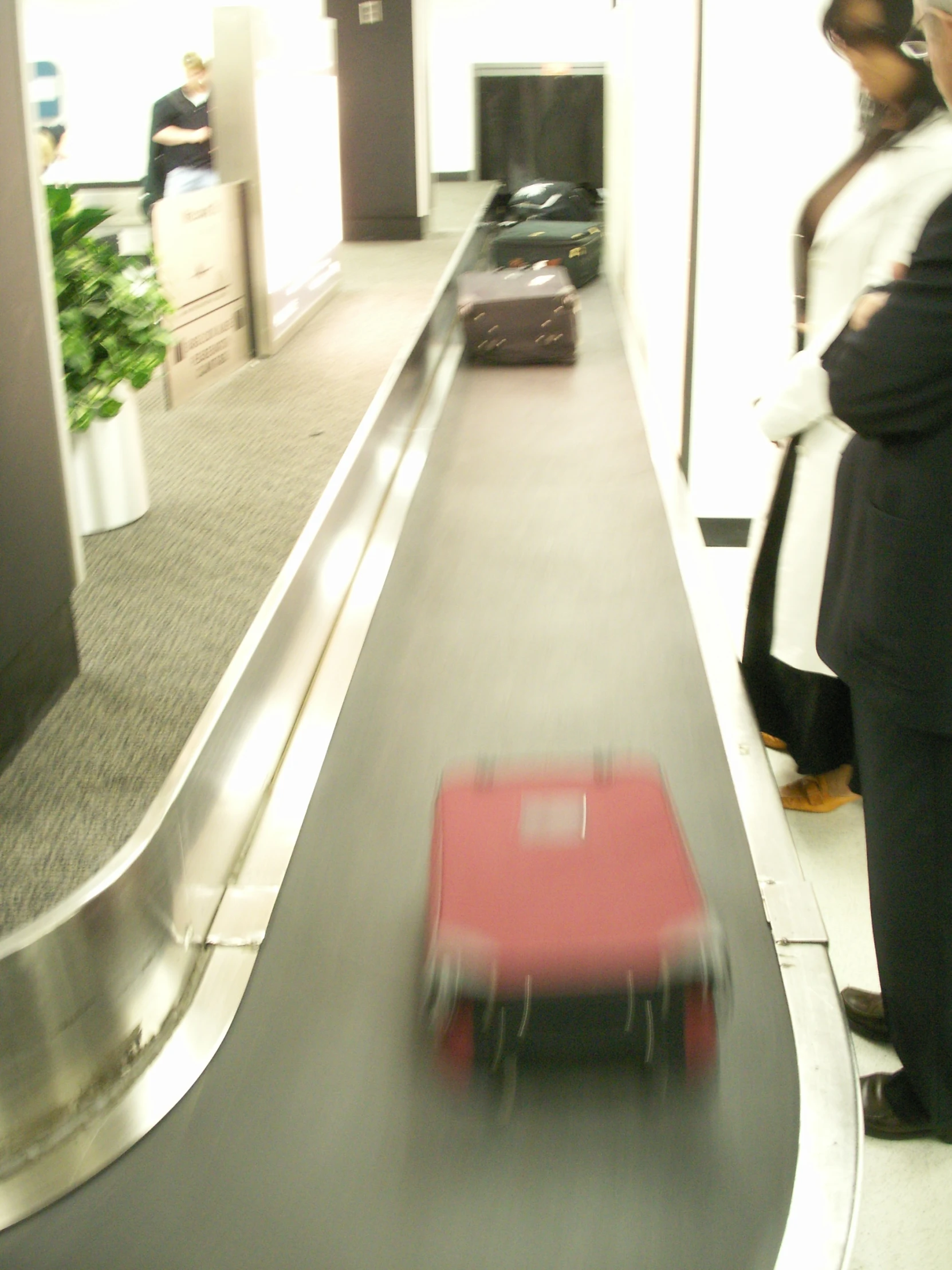 red luggage is being hed down the airport conveyor belt