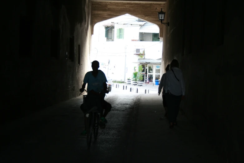 two people walking down an alley way with bikes