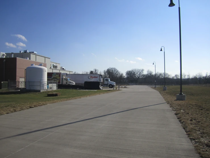 a long empty street between several buildings with a sky background