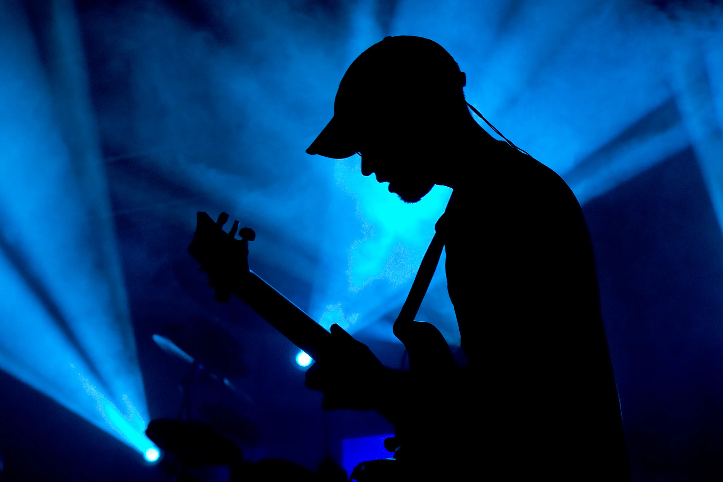 a silhouetted man playing a guitar on stage