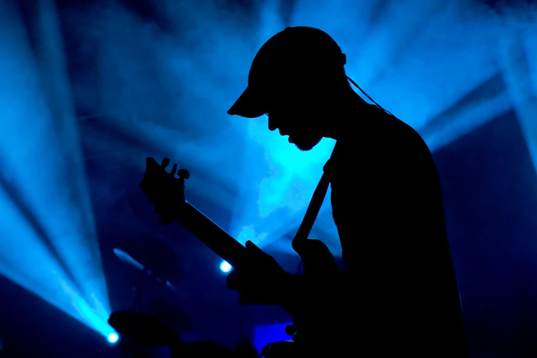 a silhouetted man playing a guitar on stage