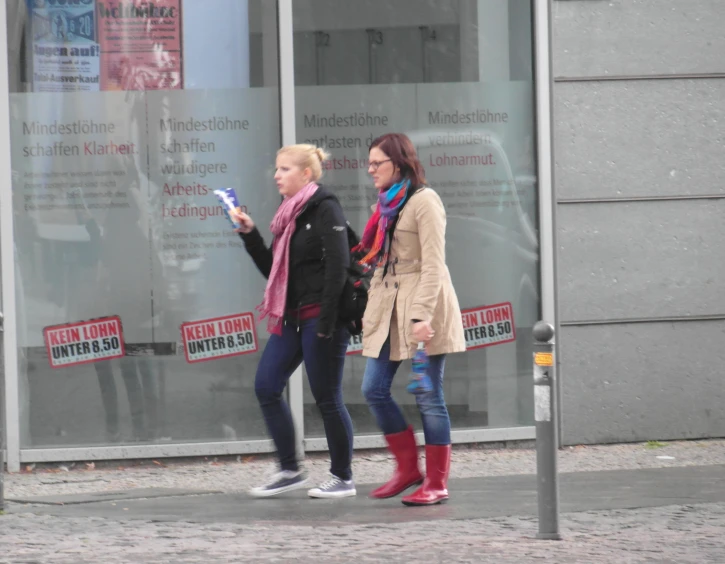 two women stand outside and are taking a pograph