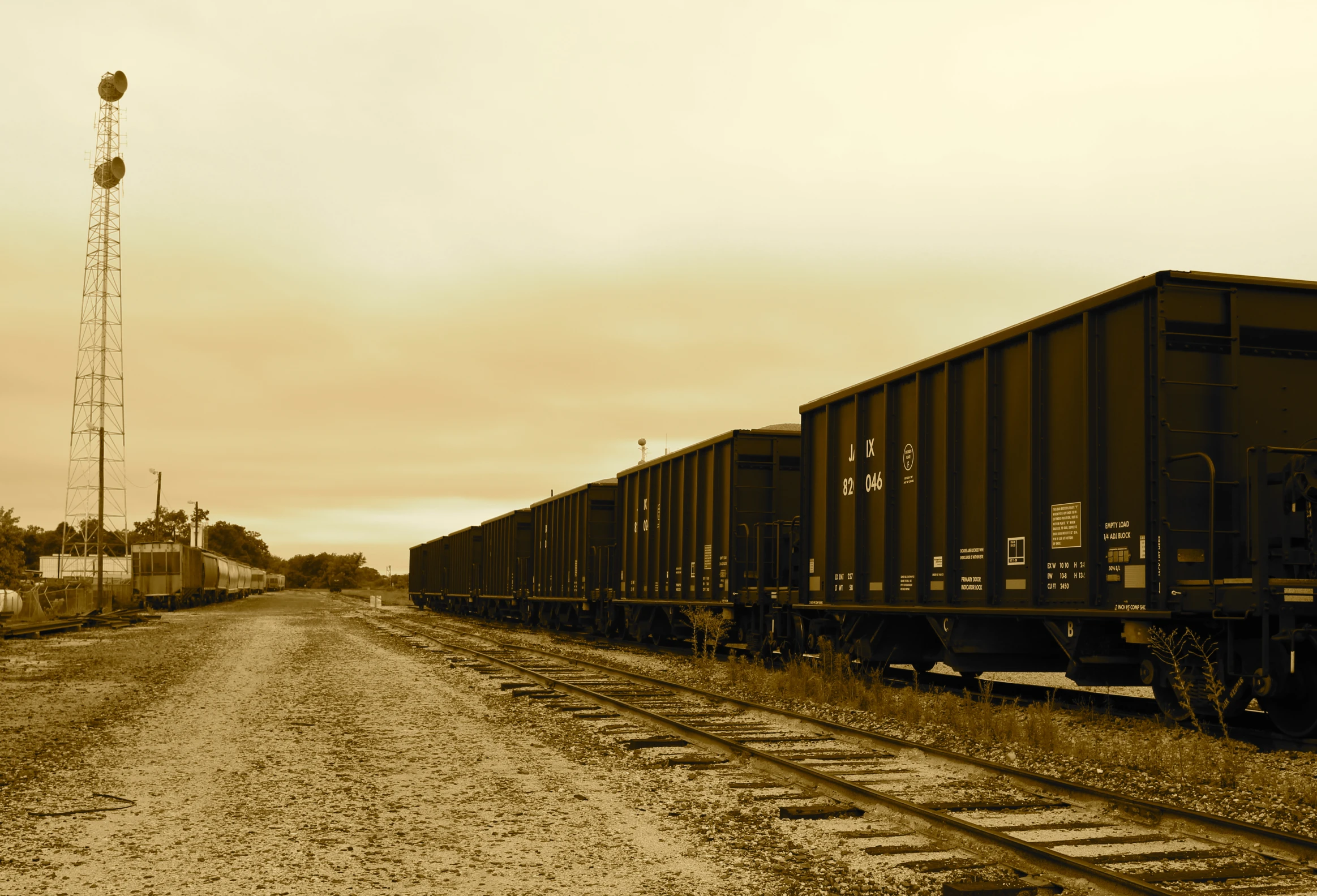 a black and white po of railroad tracks with train cars sitting by