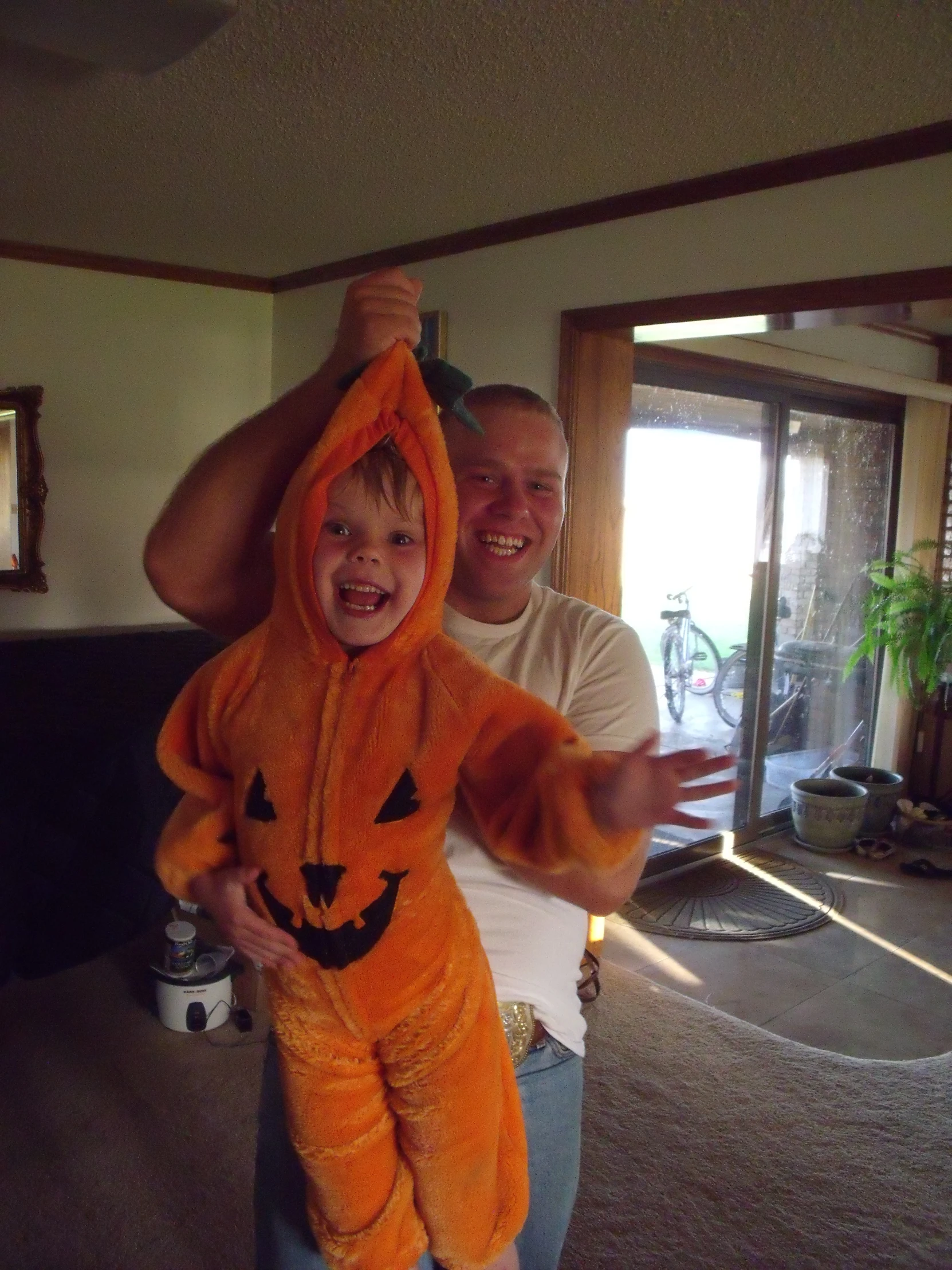 a man holding a little boy in a jack o lantern costume