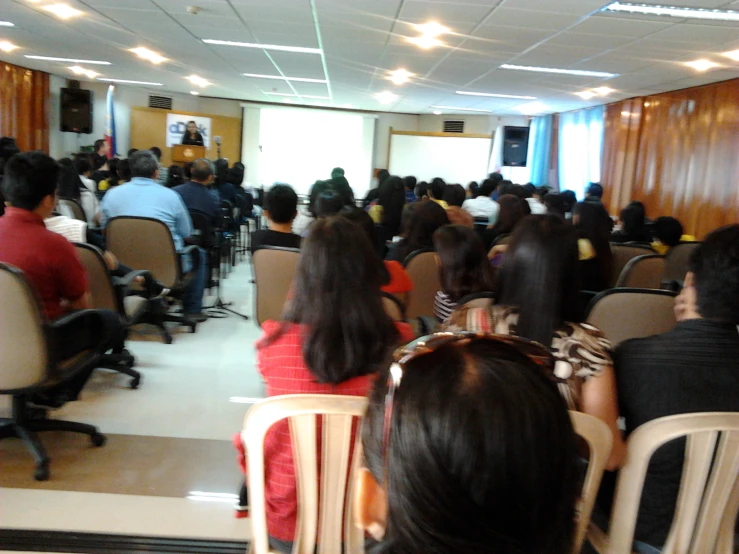 an audience of people sitting in chairs and looking at screen