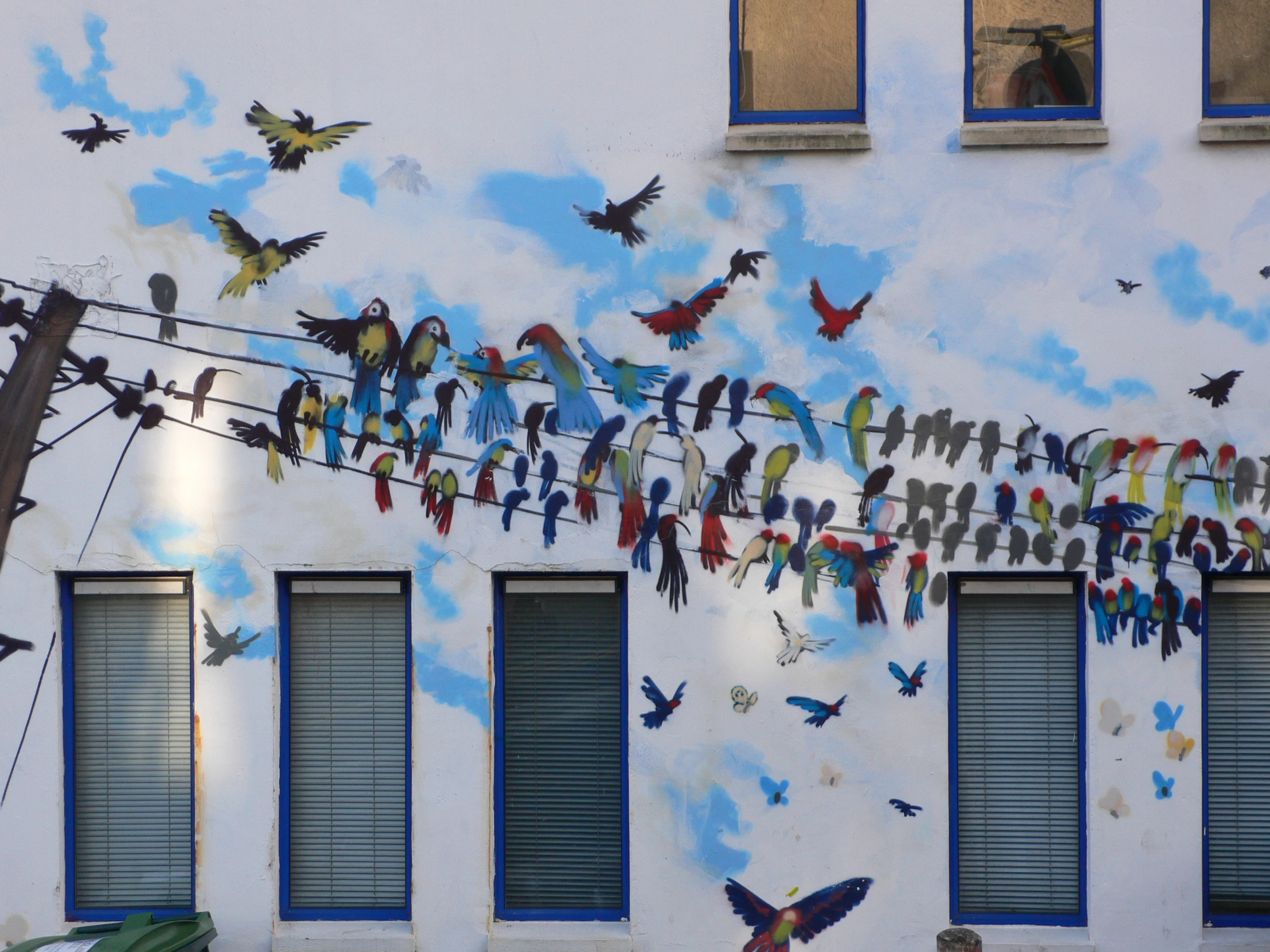 birds on clothes line painted on the side of a building