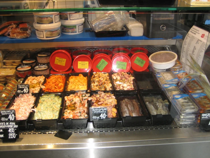 many containers and bowls of different food are displayed behind a glass