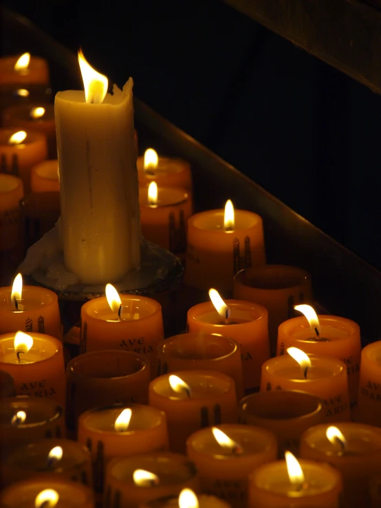 an arrangement of lit candles sit in rows on the floor