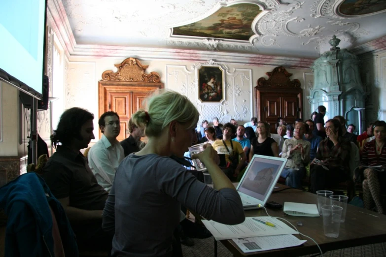 a group of people are in the room and one is using a laptop