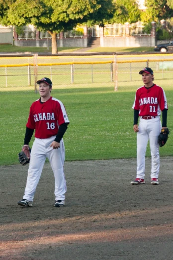 two people with baseball uniforms standing on a field