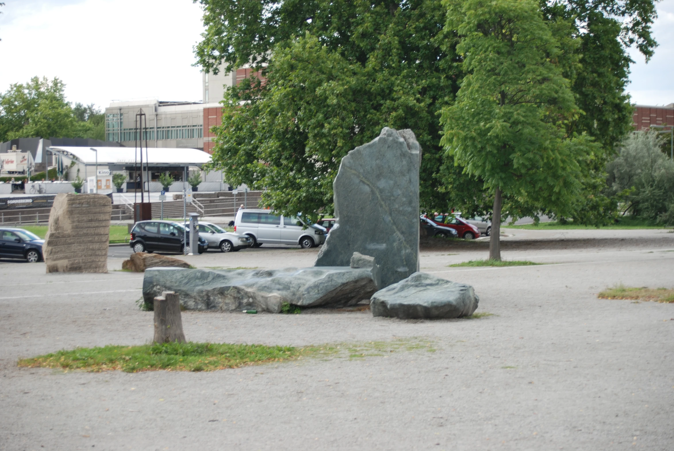 some rocks sit in a parking lot by some trees