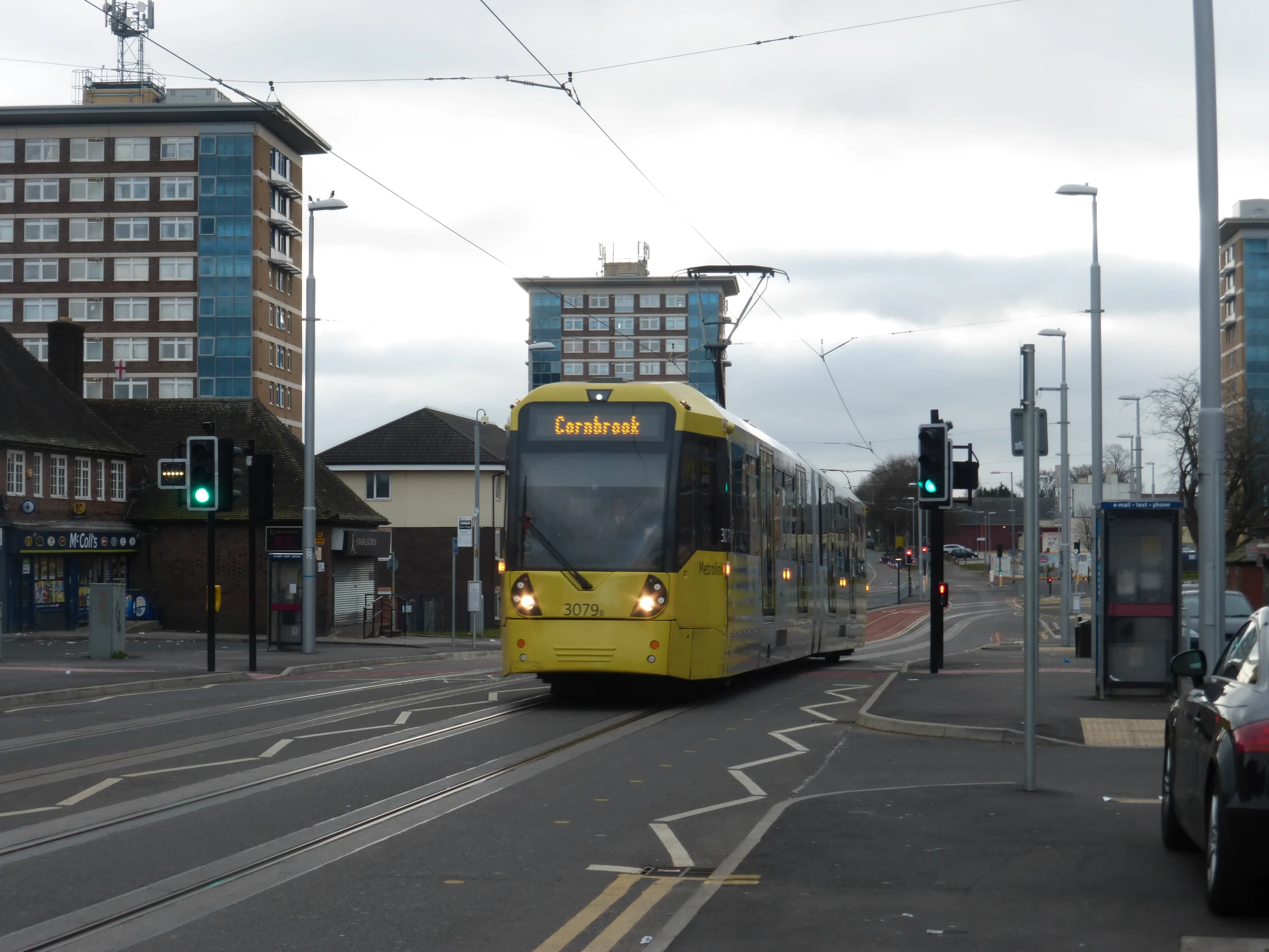 a yellow bus riding down the road near a stoplight