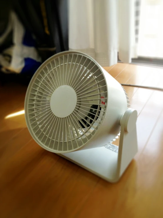 an electric fan sitting on top of a wooden table