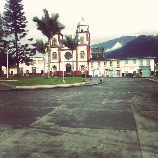 a tall church on a street with palm trees