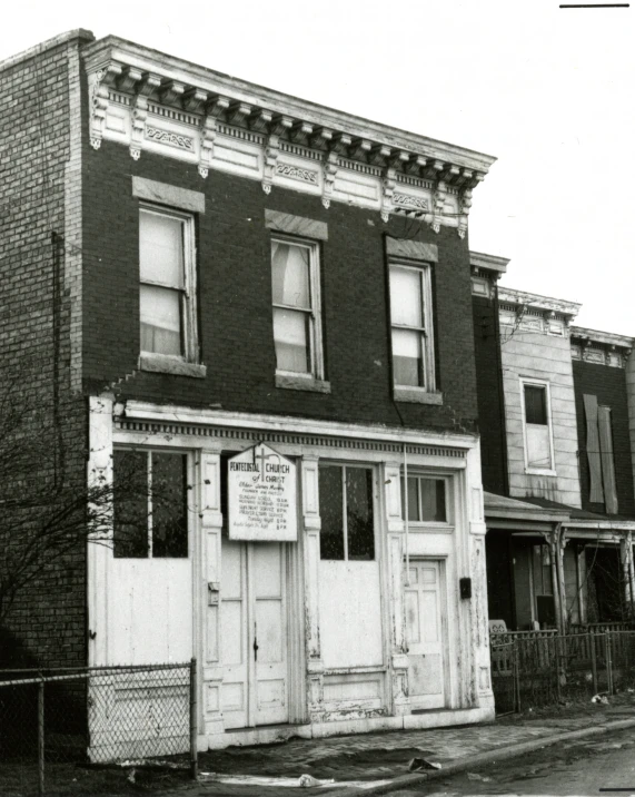 an old building sits behind a fence in front of two houses