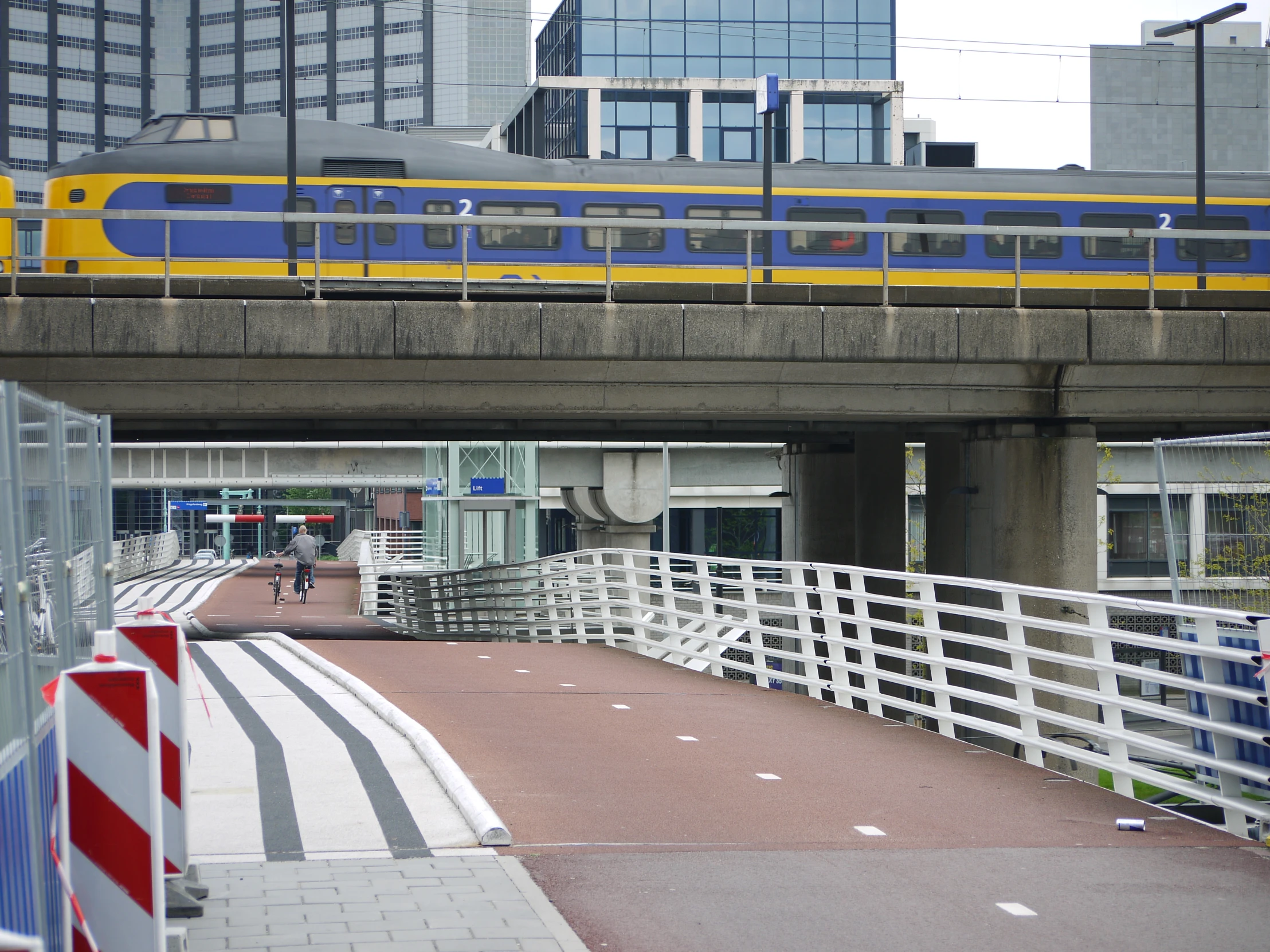 a train passing through a bridge with tall buildings in the background