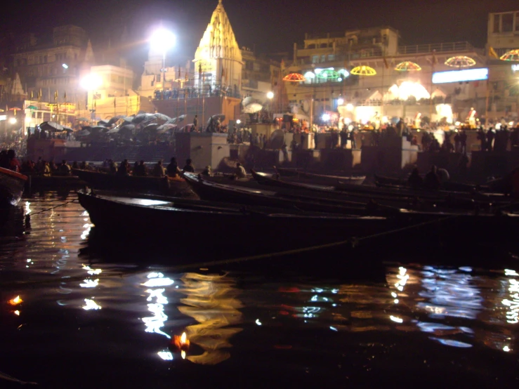 boats docked on the river at night with lights on