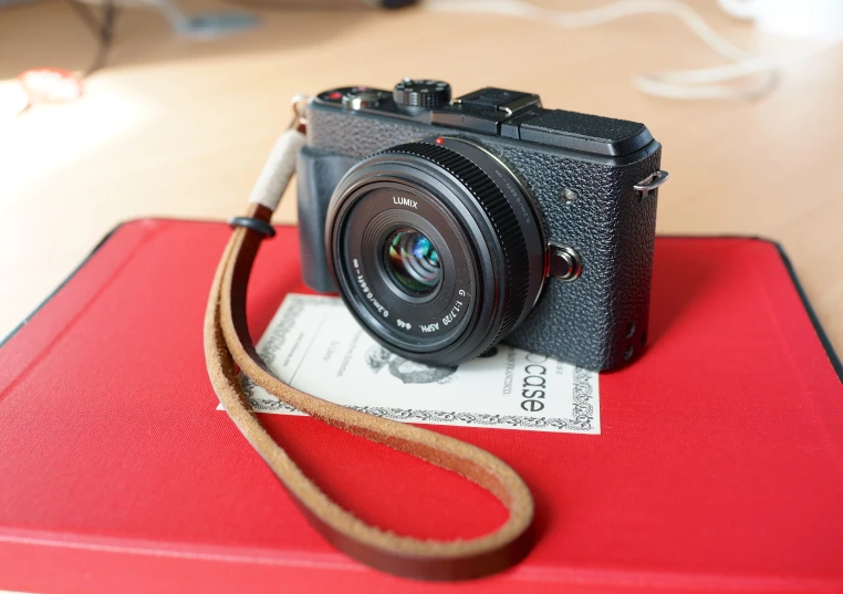 an old, broken, black camera is lying on top of a red folder