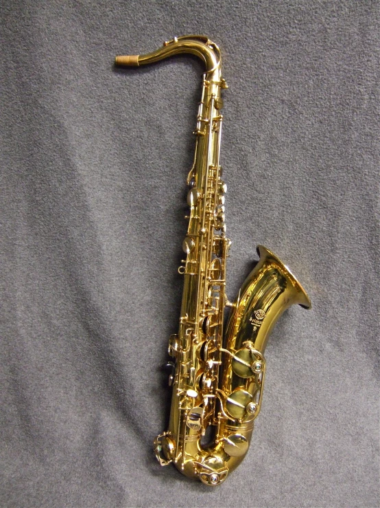 a ss saxophone sitting on a grey surface