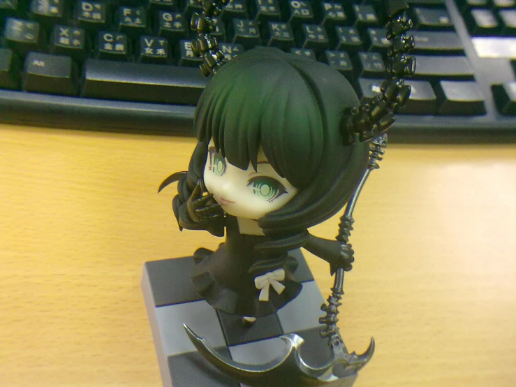 a figurine in black holding scissors on a desk