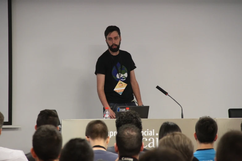 a man standing at a podium with an open laptop