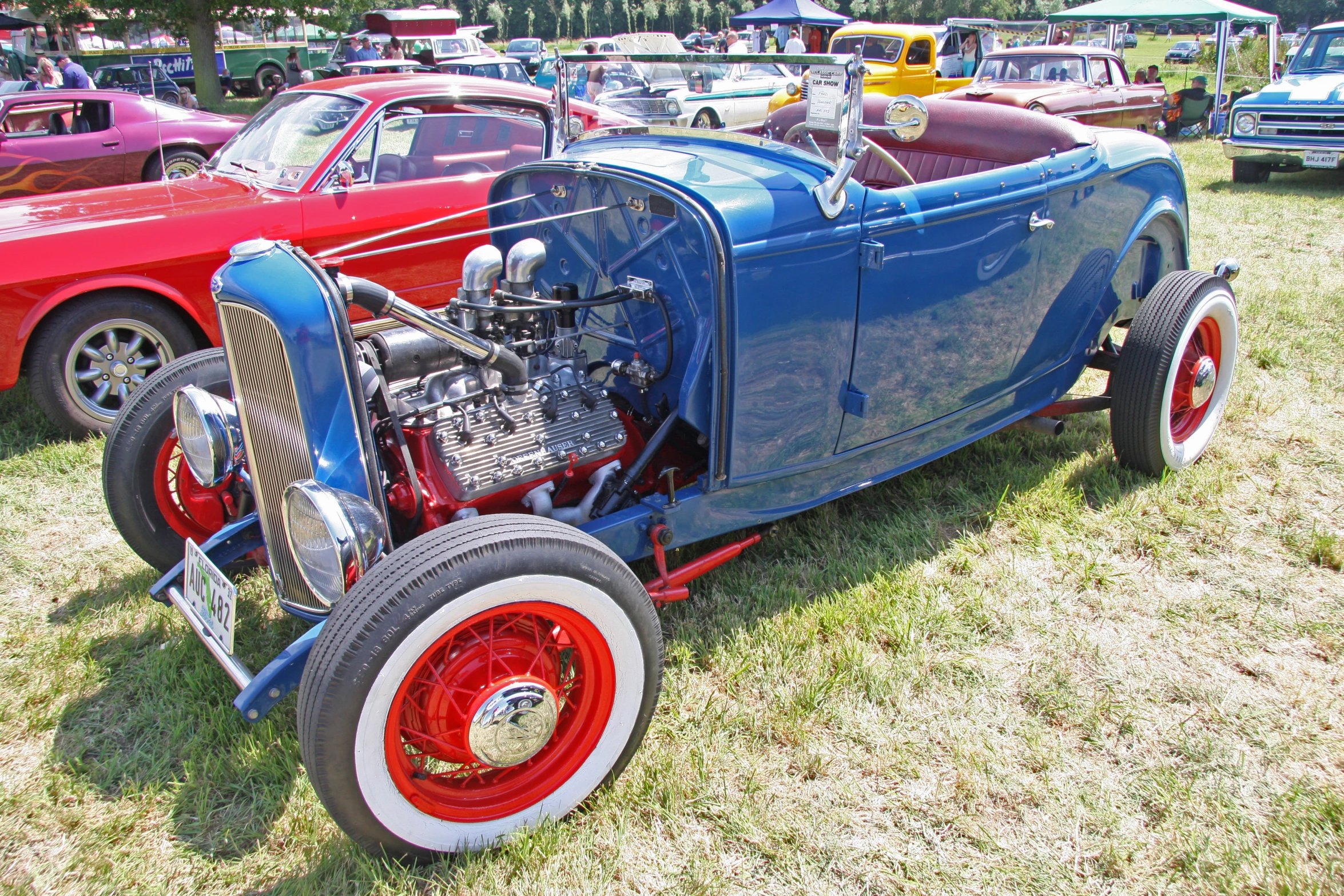 several old model cars parked in a grassy area