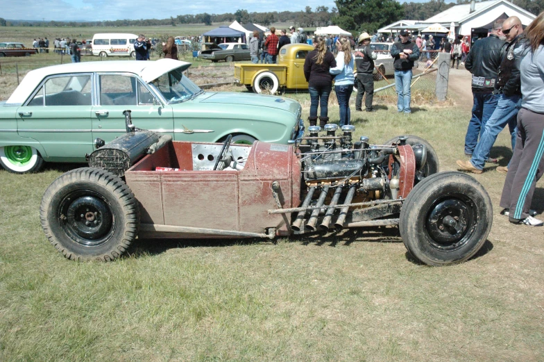 a  roded race car sitting on top of a grass covered field