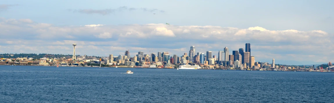 there is a boat traveling along the bay in front of the city