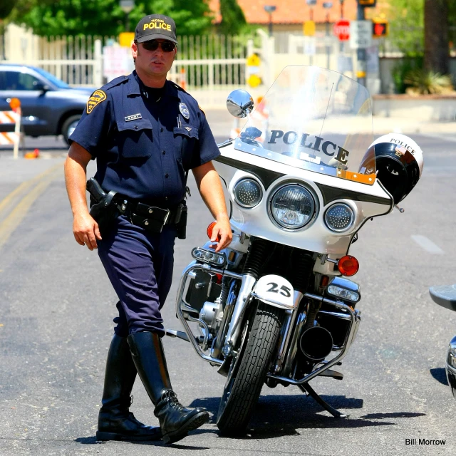 a cop wearing boots and a hat with his motor cycle