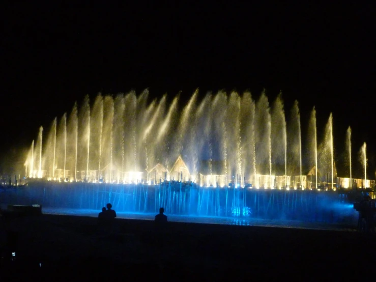 people walking near fountain with water show at night