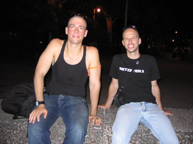 two men sitting on the curb at night time