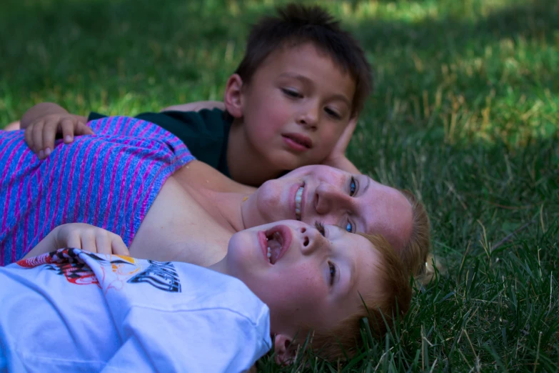 two children laying on the grass with one child looking up at the camera