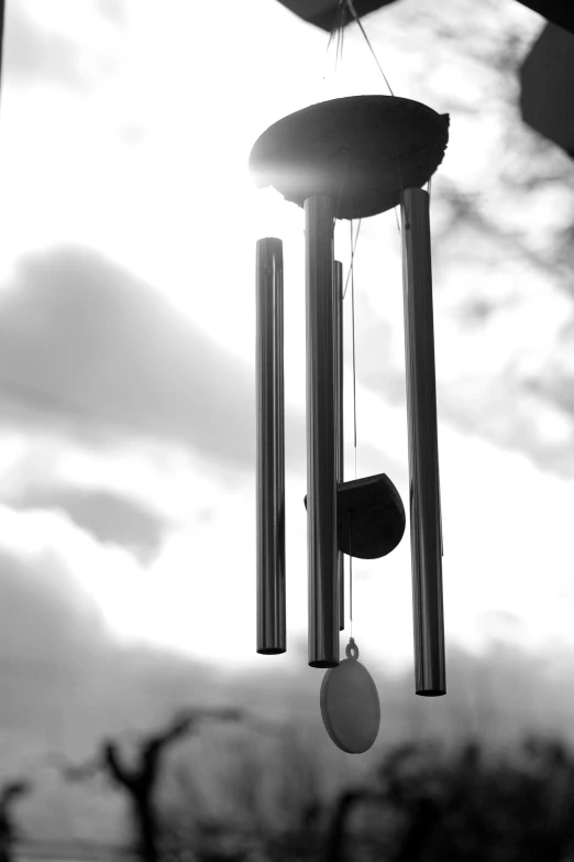 a wind chime hanging in front of the cloudy sky