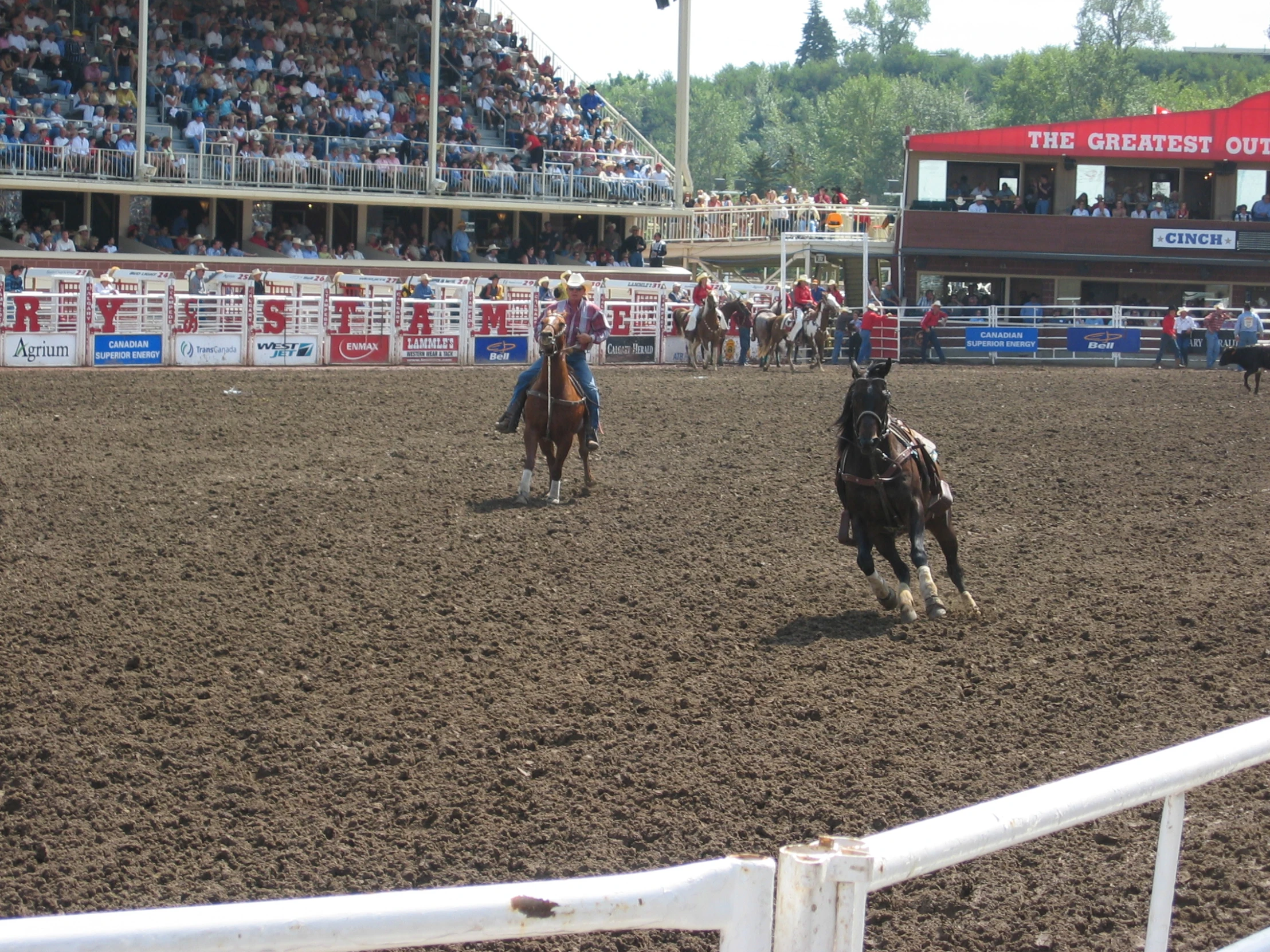 two men on horses riding through a dirt field