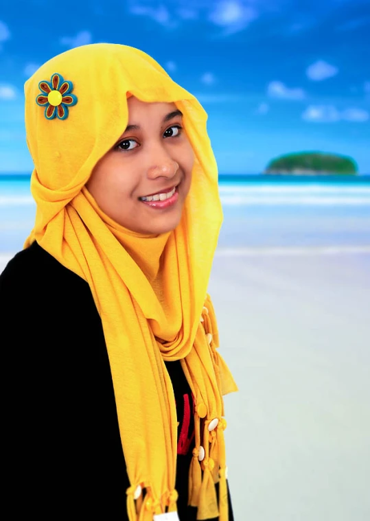 a woman standing in the sand with a yellow head scarf