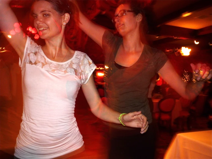 two women dancing with lights in the background