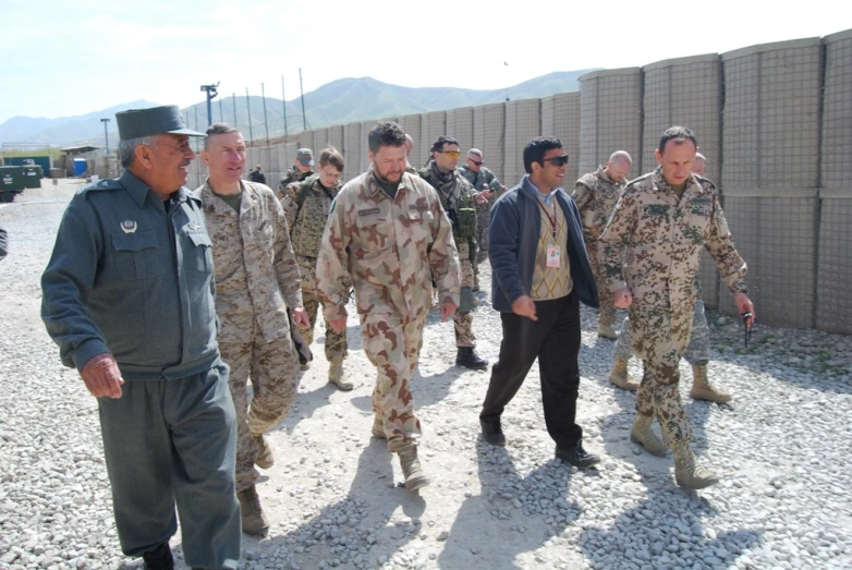 a group of military men walking along a dirt field