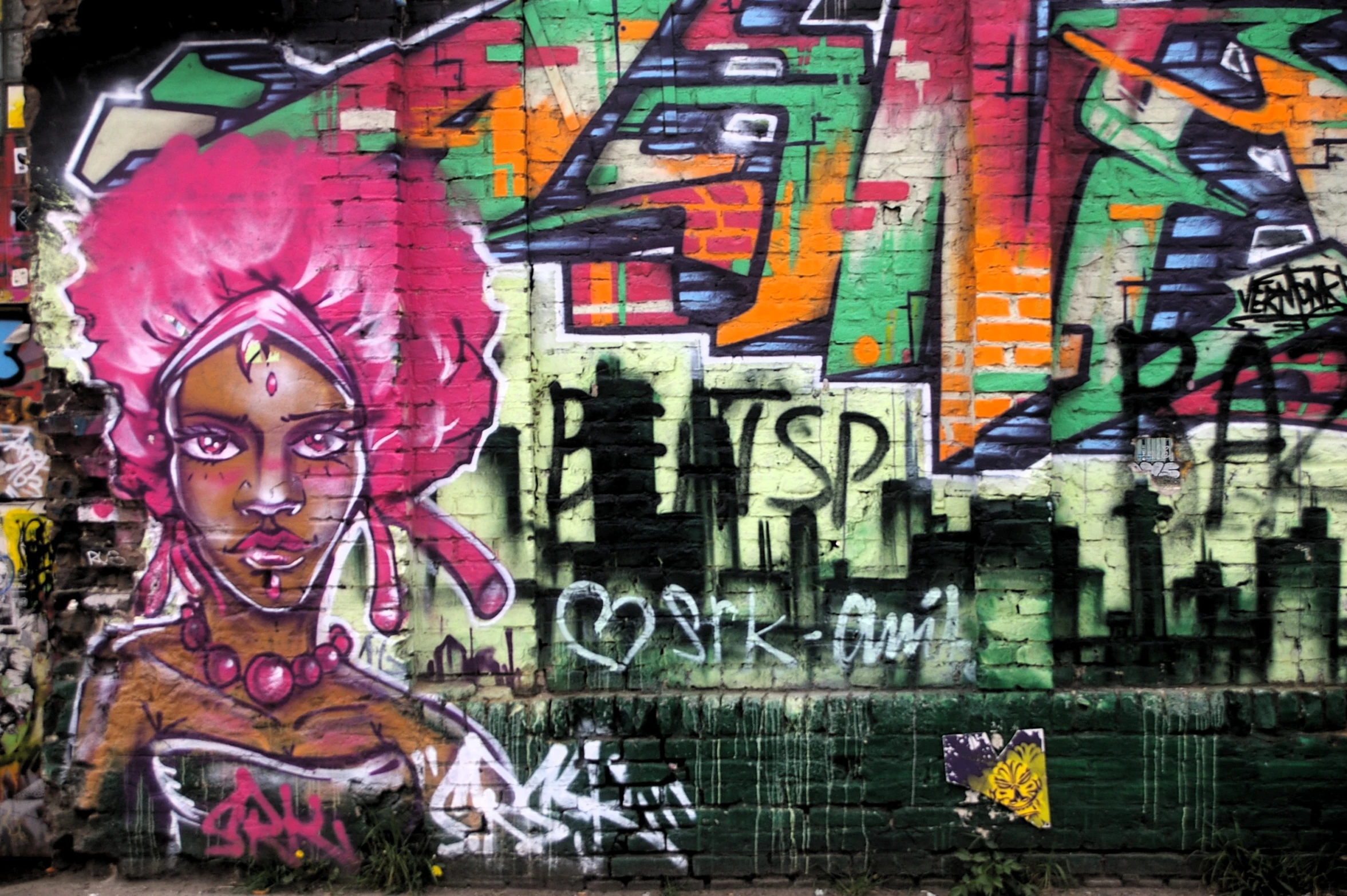 an alleyway wall decorated with graffiti is covered in multicolored graffiti